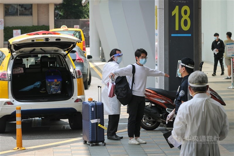 指揮中心指揮官陳時中表示,本土疫情7日已達清零標準,面對境外威脅與新變種病毒Omicron,仍需遵守防疫措施。圖為松山機場人員引導旅客搭乘防疫計程車。(中央社檔案照片)