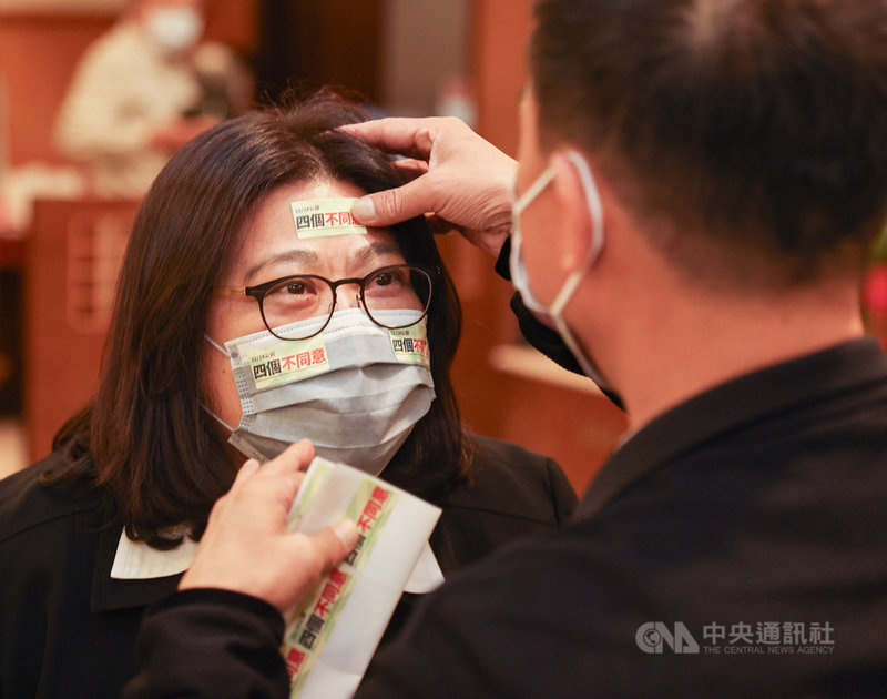 民進黨立委許智傑製作貼紙推廣公投理念,8日在記者會上為同黨立委王美惠(左)貼上,傳達「4個不同意」的公投訴求。中央社記者鄭清元攝 110年12月8日