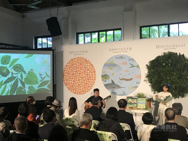 行政院農委會水土保持局出版「你知我行.里山倡議」繪本套書,12日舉行新書發表會,繪本說書人吳亭儀(右)在吉他樂聲中訴說4個農村的故事。中央社記者邱祖胤攝 110年12月12日