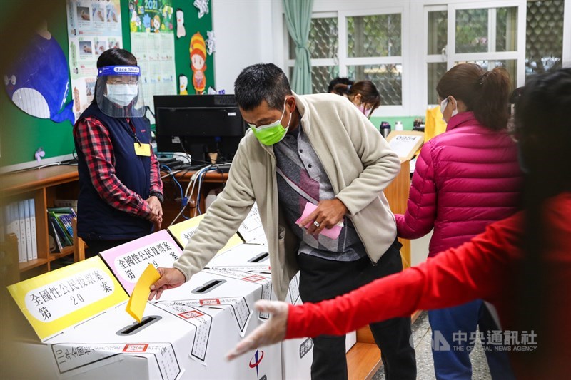 重啟核四、反萊豬、公投綁大選及三接遷離公投案18日投票，投票所選務人員配合防疫穿戴防護面罩及手套等裝備，現場引導民眾投票，讓動線更流暢。中央社記者王騰毅攝 110年12月18日