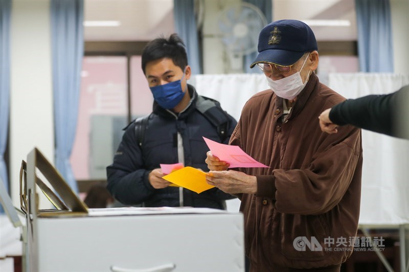 全國性公民投票案第17案至第20案18日登場,民眾陸續前往投開票所完成投票。今年公投選票以不同顏色區分4大公投案,選務人員也在旁提醒民眾將選票投至正確票箱。中央社記者裴禛攝 110年12月18日