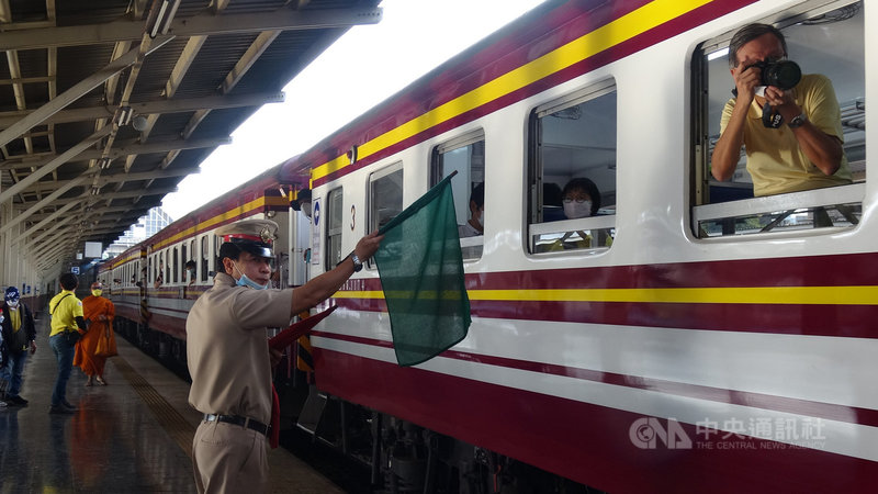 泰國最古老的火車站華藍蓬即將在23日讓出泰國火車運輸中心的地位，交棒新落成的挽賜車站。圖為列車出發時車站工作人員高舉綠色旗幟，代表可以安全出發。中央社記者呂欣憓曼谷攝 110年12月20日