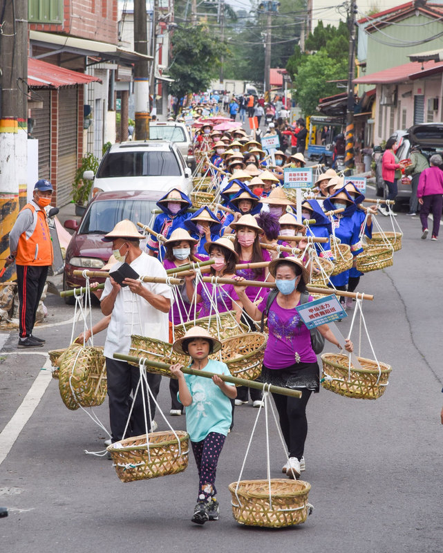 屏東縣政府客家事務處26日在高樹鄉東振開基伯公前廣場,舉行六堆300慶典「㧡擔團圓大滿福」活動,六堆12鄉區以客家人農忙時的「挑擔奉飯」精神遊行入庄。(屏東縣政府提供)中央社記者郭芷瑄傳真 110年12月26日