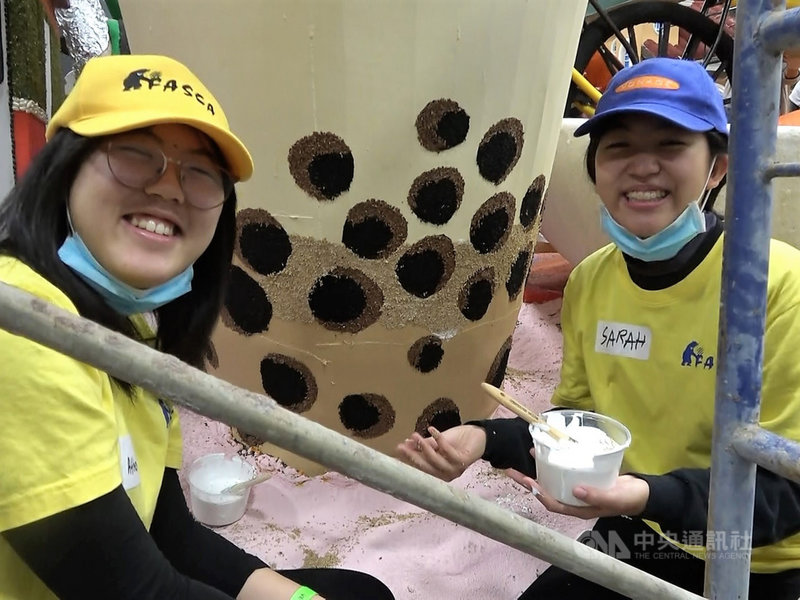 參與僑委會「海外青年志工」（FASCA）計畫的台裔高中生雅典娜（Athena）（左）、莎拉（Sarah）29日為玫瑰花車遊行當義工，布置中華航空的台灣特色花車，兩人在巨大的珍珠奶茶前合影。中央社記者林宏翰洛杉磯攝 110年12月30日