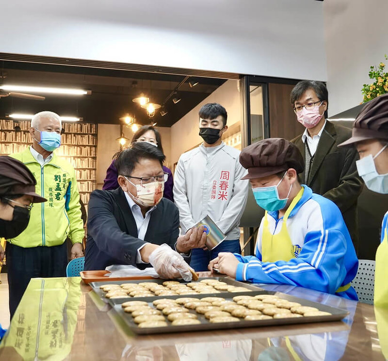 屏東縣政府在東港鎮東新國中設立第2所不同職業類群試探體驗中心,13日舉辦揭牌儀式,落實生涯發展從小扎根提早試探。圖為學生帶領縣長潘孟安(前左,西裝者)體驗製作餅乾。(屏東縣政府提供)中央社記者郭芷瑄傳真 111年1月13日