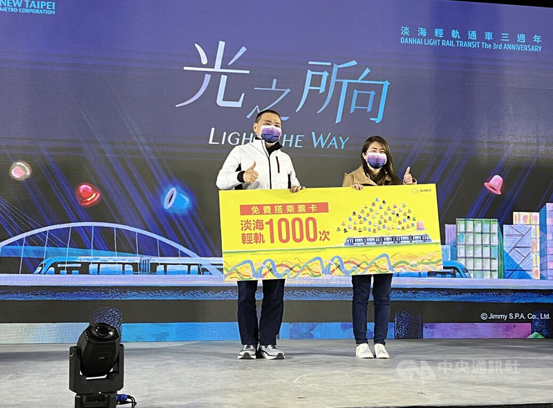 新北淡海輕軌3週年光影列車秀15日晚間登場,活動並邀來輕軌第1000萬名幸運兒乘客林小姐(右),由市長侯友宜(左)送上象徵可免費搭乘1000趟次的看板。林小姐笑說,她搬到淡水2年,沒想到會成為第1000萬名乘客。中央社記者沈佩瑤攝 111年1月15日