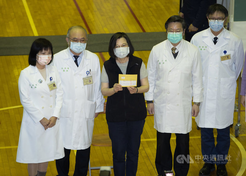 總統蔡英文(中)15日一早到台大醫學院體育館完成接種第3劑高端疫苗,秀出疫苗接種紀錄卡。中央社記者謝佳璋攝 111年1月15日