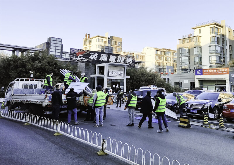 中國北京市15日晚間通報,海淀區新增1例本土確診病例,經基因測序檢出Omicron。圖為工作人員在個案居住的社區門口搭建圍擋。(中新社)