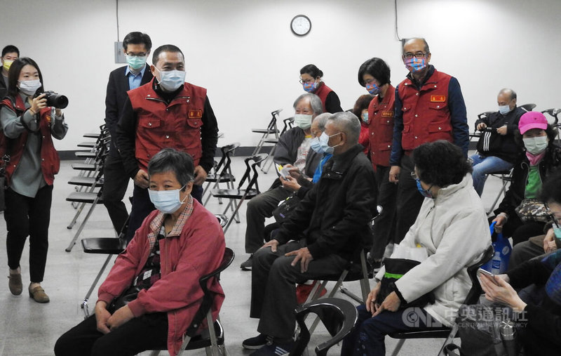 新北市針對全市44萬7000名65歲以上長者展開第3劑COVID-19疫苗接種,新北市長侯友宜(立者左2、紅背心者)18日前往視察施打情形並向長者致意。中央社記者王鴻國攝 111年1月18日