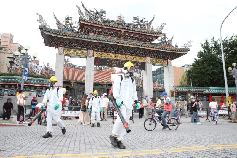 去年5月中旬本土社區流行疫情嚴峻,市府環保局人員全副武裝,針對龍山寺周邊等地區加強噴消。(中央社檔案照片)