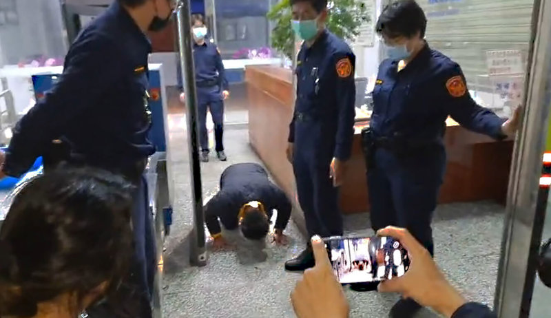 台鐵太魯閣號事故被告李義祥(跪地者)21日晚間完成交保,欲離開時等候在外的罹難者家屬激動上前要他道歉,場面混亂,李義祥一度被推倒,隨後狼狽跑回地院,約30分鐘後再次走出,向家屬下跪磕頭連說「對不起」。(民眾提供)中央社記者張祈傳真 111年1月21日