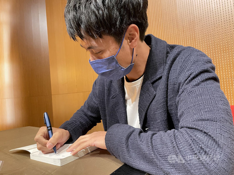 中職中信兄弟隊投手官大元自傳「逆轉的王牌:官大元」上市,22日舉行新書分享會,書中不僅寫大家熟識的職棒球員身分,也寫出他的成長過程。圖為官大元為書迷朋友簽書。中央社記者謝靜雯攝 111年1月22日