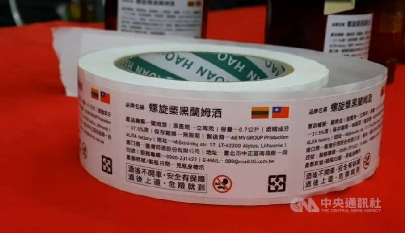台酒人員撕下瓶身中國簡體字版標貼,改以印有台灣、立陶宛國旗的繁體中文標貼取代。中央社記者吳佳蓉攝 110年1月22日