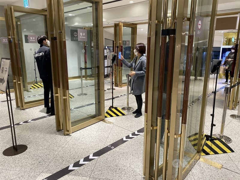 儘管韓國疫苗接種率很高,並已延長實施COVID-19防疫限制,23日仍通報7630例新增確診,寫下疫情爆發至今次高紀錄。圖為首爾在百貨公司入口處掃描QR code的民眾。(中央社檔案照片)