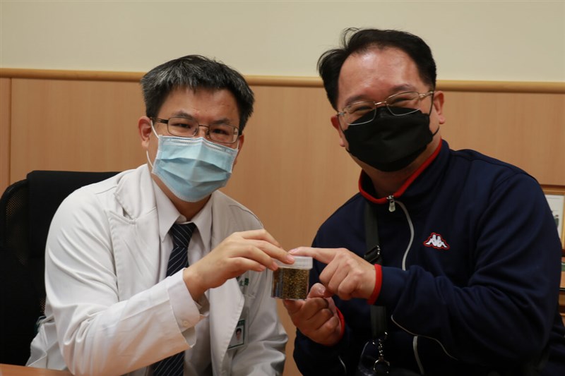 台中慈濟醫院醫師余政展(左)拿著自膽囊取出的一整瓶膽結石,叮嚀病人清淡飲食。(民眾提供)中央社記者趙麗妍傳真 111年1月25日