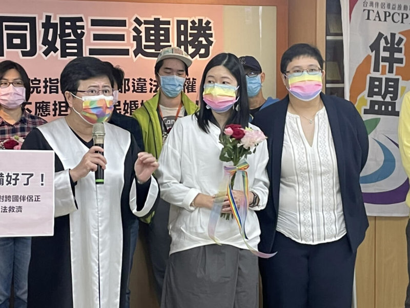 台灣、新加坡跨國同性伴侶小C(前中)與美蘋(前右)26日到台北松山戶政事務所登記結婚,成為第3對打官司獲准結婚的跨國同性伴侶。前左為台灣伴侶權益推動聯盟律師團召集人許秀雯。(伴侶盟提供)中央社記者吳欣紜傳真 111年1月26日