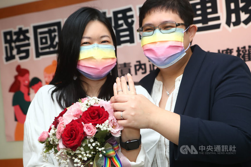 台灣、新加坡跨國同性伴侶小C(左)與美蘋(右)26日到台北松山戶政事務所登記結婚,兩人開心秀出手上婚戒,現場洋溢著幸福氛圍。中央社記者王騰毅攝 111年1月26日