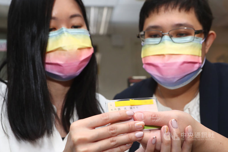 台灣、新加坡跨國同性伴侶小C(左)與美蘋(右)因登記結婚遭拒興訟獲勝訴,26日登記結婚、成為第3對打官司獲准結婚的跨國同性伴侶。圖為兩人出示身分證,配偶姓名已標註在配偶欄。中央社記者王騰毅攝 111年1月26日