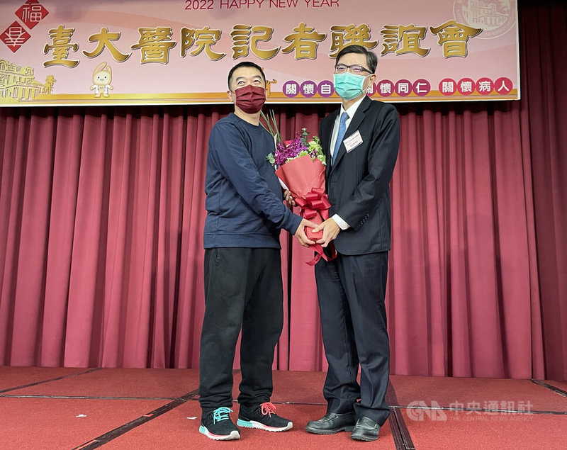 台大醫院28日舉辦記者會說明尖端醫療發展成果,包含完成亞洲首例主動脈組織工程氣管移植手術,癌醫中心分院副院長陳晉興(右)會中並獻花恭喜患者重生。中央社記者江慧珺攝 111年1月28日