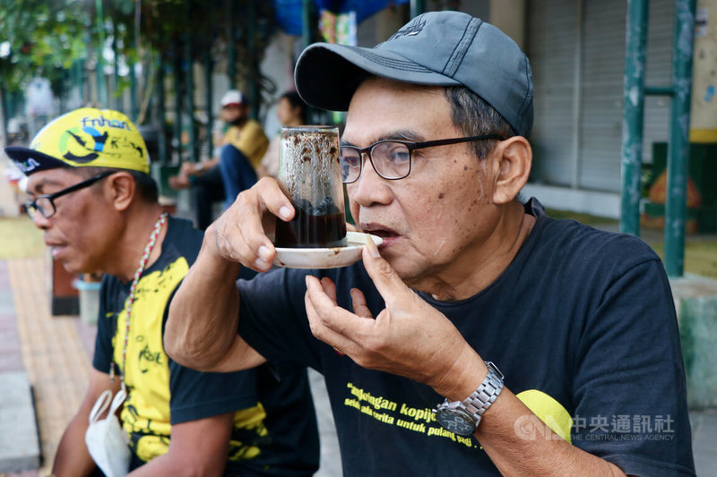 印尼中爪哇古都日惹特有的Kopi Joss深受當地人喜愛,忠實老客戶西斯沃示範Kopi Joss的喝法。攝於110年10月14日。中央社記者石秀娟日惹攝 111年2月2日