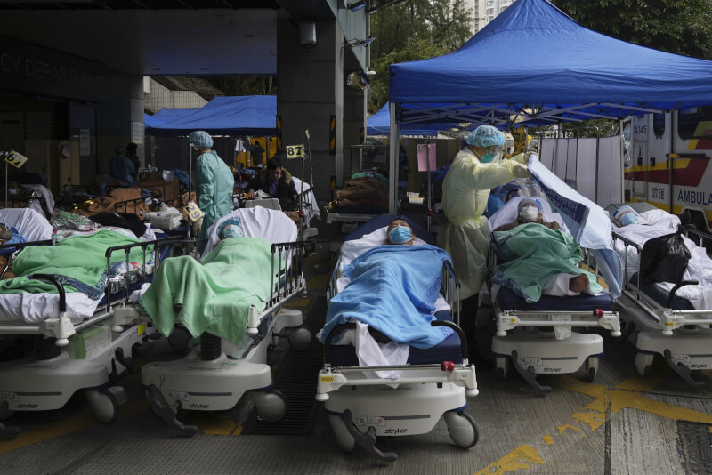 香港3月3日通報新增5萬6827例COVID-19確診案例。圖為2月18日香港明愛醫療中心外的臨時治療區，患者躺在病床上等待。（美聯社）