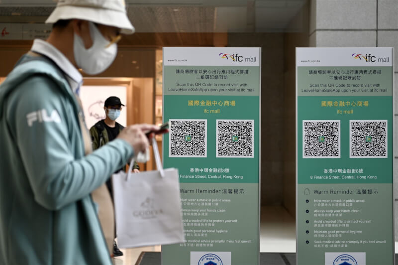 COVID-19疫情流行,香港新增確診病例首度破萬。圖為24日香港民眾進入百貨商場前先掃描疫苗通行證。(中新社)