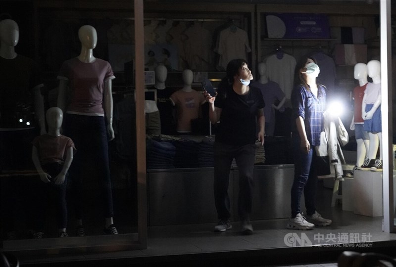 高雄一處受影響的服飾商家,員工以手機燈光輔助整理店內環境。中央社記者董俊志攝 111年3月3日