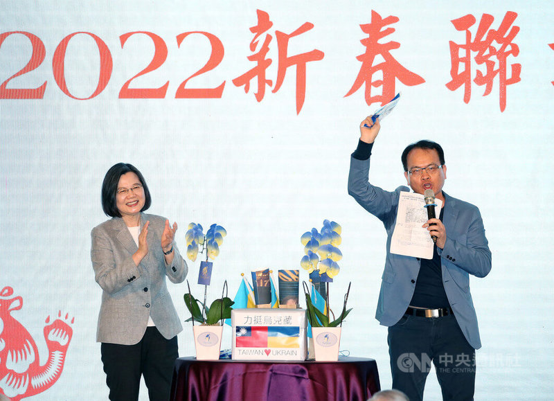 總統蔡英文(左)13日出席「台灣之友會感恩迎新春聯歡之夜」,現場由媒體人鄭弘儀(右)主持義賣,拍賣蔡總統親筆簽名的烏克蘭國旗顏色式樣口罩,5袋口罩拍賣所得新台幣52萬元捐給烏克蘭。中央社記者郭日曉攝 111年3月13日