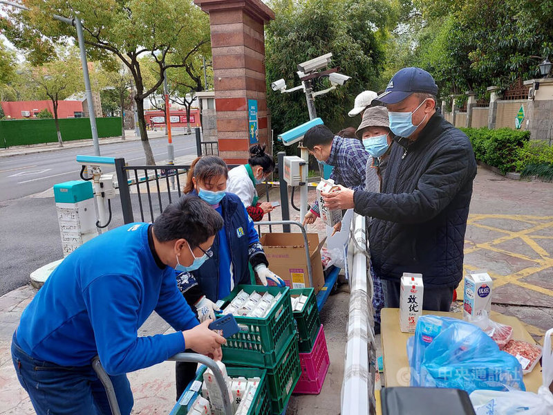 上海疫情連帶衝擊生鮮電商平台營運，在供不應求的情形下，不少民眾無法在平台上買菜，只好等著附近的商家上門賣菜，或是自行在在微信上籌組「買菜團」。圖為上海一個封閉社區門口，上門賣菜的商家與採購人潮。中央社記者張淑伶上海攝  111年3月24日