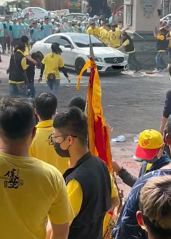雲林縣北港武德宮前廣場9日發生進香團鬥毆事件,場面混亂,現場一輛白色賓士車一度衝到鬥毆人群中,馬上就被鐵棒敲打,賓士車隨即又急速倒車離開。(民眾提供)中央社記者黃國芳傳真 111年4月9日