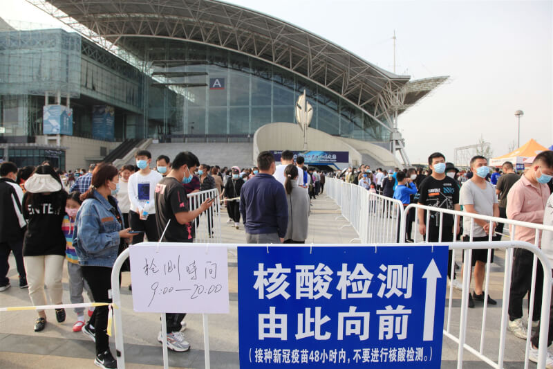 中國官方10日通報新增病例數2萬6462例,這是自3月疫情大爆發以來,連續第5天新增病例數破2萬。圖為大批民眾9日在南京國際展覽中心外排隊等候採檢。(中新社)