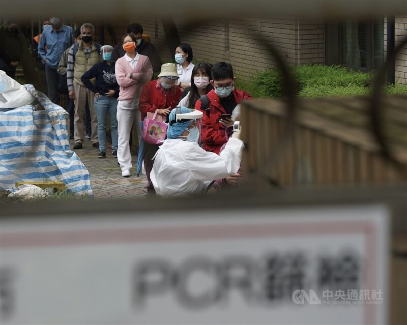國內COVID-19確診人數不斷創新高,指揮中心擬增加篩檢代替隔離適用對象,確保社會運作。圖為台北市北投一家醫院醫護人員替排隊民眾量測額溫。中央社記者徐肇昌攝 111年4月21日