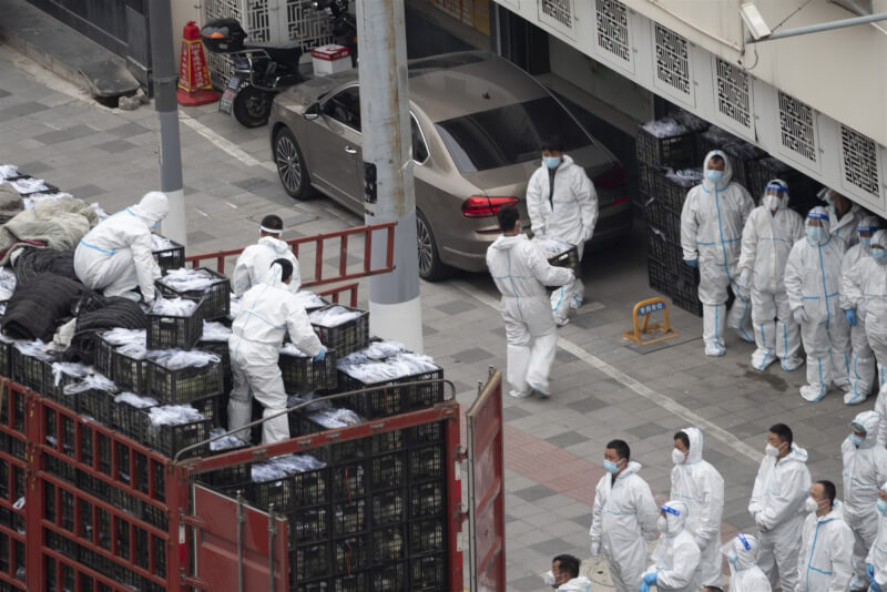 圖為去年4月上海楊浦區街頭防疫人員搬運物資。（中新社）