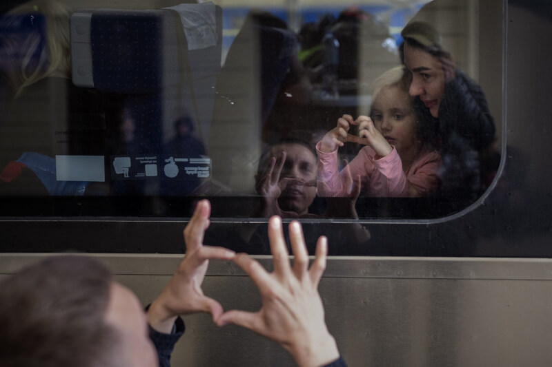 圖為22日烏克蘭男子向開往​​波蘭逃離戰爭火車上的妻子及4歲女兒道別。（美聯社）