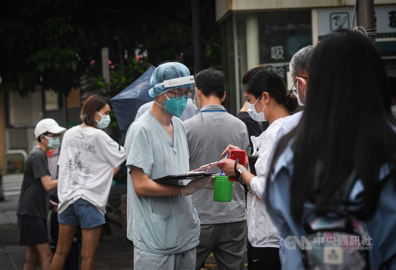 台北市確診者簡訊通報系統上路,市府說明,醫院驗出PCR陽性後,就會以簡訊通知個案填問卷回報接觸史。圖為民眾前往台北市一處篩檢站進行採檢,醫護人員協助民眾填寫資料。(中央社檔案照片)