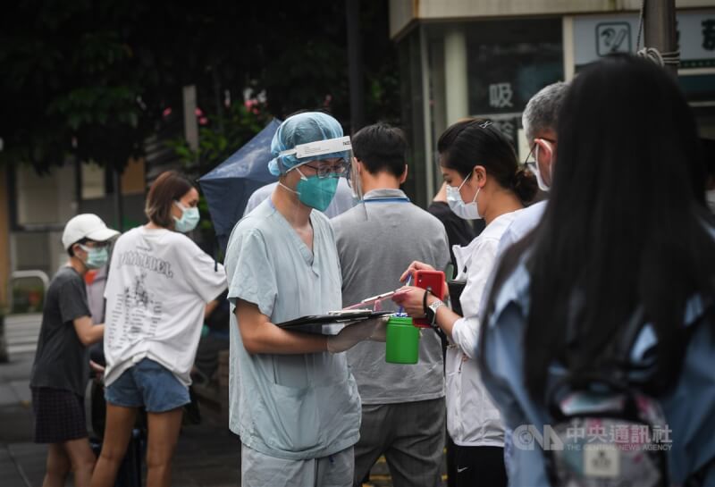 中央流行疫情指揮中心27日宣布，國內新增8822例本土病例。圖為民眾前往台北市一處篩檢站進行採檢，醫護人員協助民眾填寫資料。（中央社檔案照片）