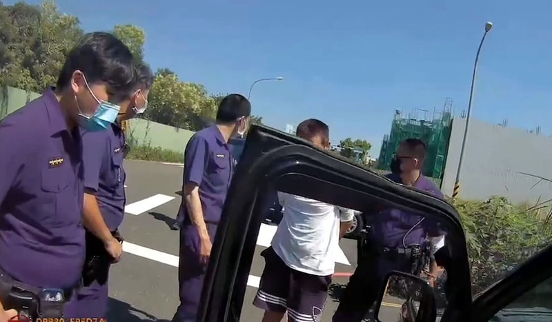 嘉義市毒品通緝犯陳姓男子(白衣者)27日駕車連續衝撞欲攔查的多名員警後加速逃逸,員警開6槍打中陳男車輛輪胎,陳男棄車躲在工地仍難逃法網,全案訊後依法送辦。(警方提供)中央社記者黃國芳傳真 111年4月27日
