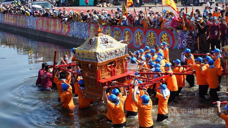 嘉義縣布袋鎮新塭嘉應廟百年傳統民俗「沖水路、迎客王」活動,27日在新塭王船碼頭登場,神轎一一衝進水裡,場面熱鬧。中央社記者蔡智明攝 111年4月27日