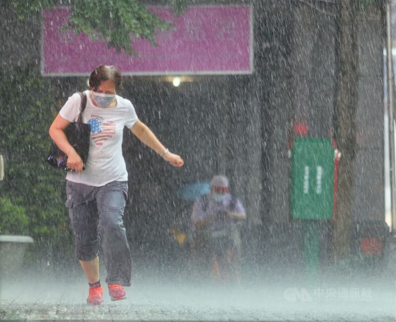 氣象局預測今年梅雨季各地雨量以正常至偏少機率較大，降雨時間將更集中、強度也可能更強，提醒民眾除應節約用水外，也須防強降雨。圖為北市民眾冒雨前行。（中央社檔案照片）