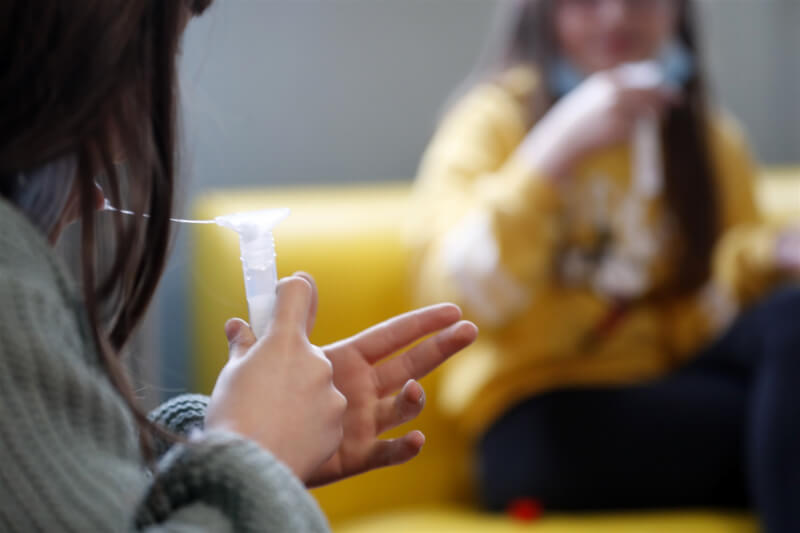 食藥署29日下午核准國內首款家用唾液快篩試劑，原產國為南韓，經效能驗證確認PCR陽性一致率達95.83%。圖為法國一名孩童吐唾液到採樣管裡。（美聯社）