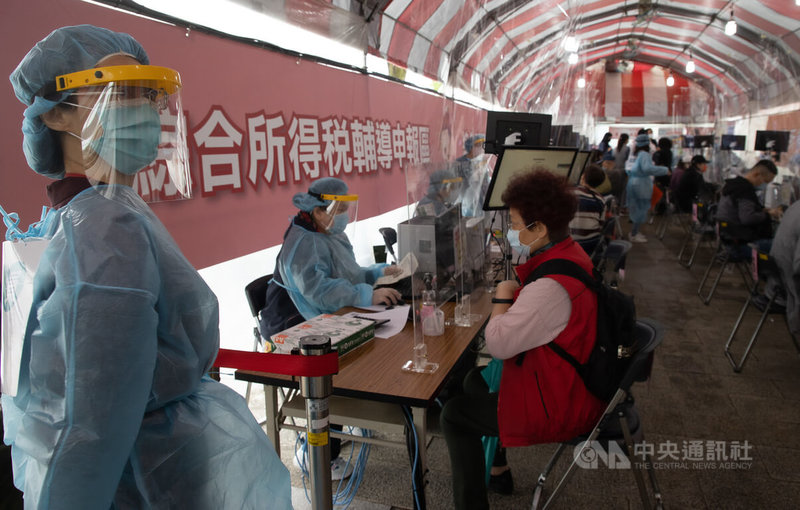 國內COVID-19疫情嚴峻,台北國稅局在戶外進行報稅分流,2日工作人員穿上防護裝備,全副武裝,協助民眾報稅。中央社記者謝佳璋攝 111年5月2日