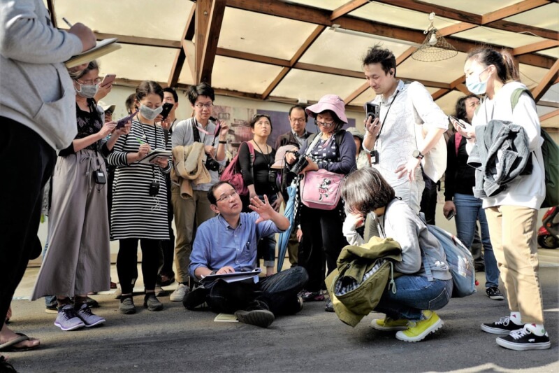 渡邉義孝認為素描老建築,能開啟與人們相繫的魔法,他也把握每一次機會與當地人溝通。圖為他在新竹被人群包圍的場景。(渡邉義孝提供)