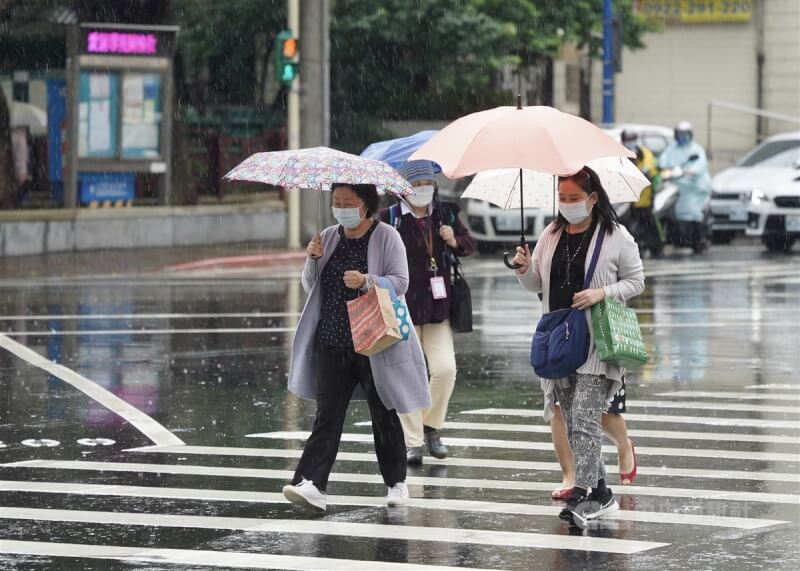 氣象專家吳德榮說，13至16日滯留鋒徘徊，防致災性降雨。圖為民眾撐傘走在台北市士林區的街頭。（中央社檔案照片）