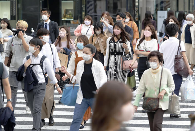日本首相岸田文雄12日說，民眾在戶外若能保持足夠社交距離，就推薦脫掉口罩。圖為4月底東京街頭戴口罩的民眾。（共同社）