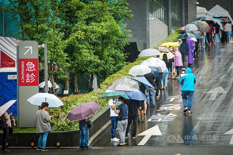 圖為11日新北市土城區一間醫院外民眾冒雨撐傘排隊等待篩檢。中央社記者王騰毅攝 111年5月11日