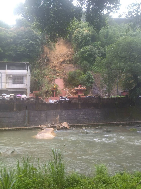 新北市消防局14日下午獲報,在石碇區石碇西街的土地公廟後方土石滑落,崩塌面積約長度15公尺、寬25公尺、高度20公尺,約6到7層樓高,所幸無人受傷,警方已到場進行交通管制。(民眾提供)中央社記者沈佩瑤傳真 111年5月14日