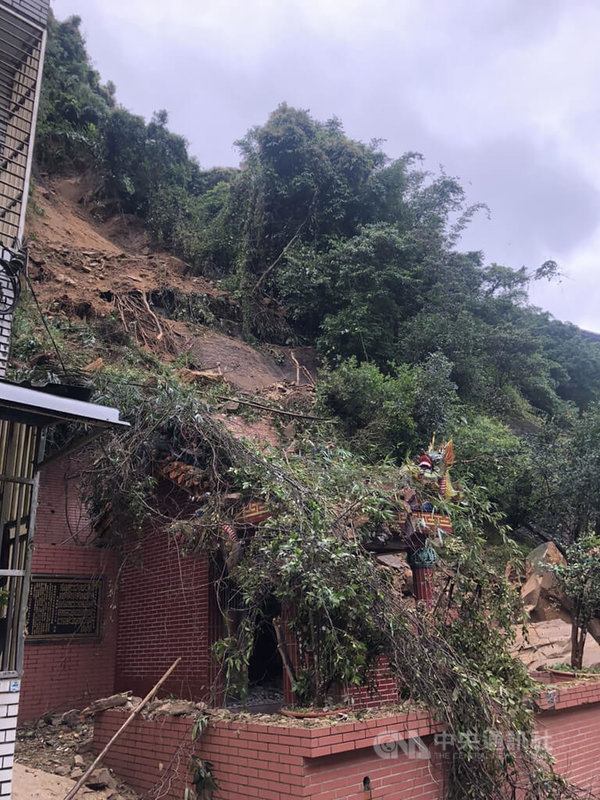 新北市石碇區石碇西街的土地公廟後方14日下午發生大量土石滑落,崩塌面積約長度15公尺、寬25公尺、高度20公尺,約6到7層樓高,幸無人受傷,但土地公廟已半毀。(翻攝畫面)中央社記者沈佩瑤傳真 111年5月14日