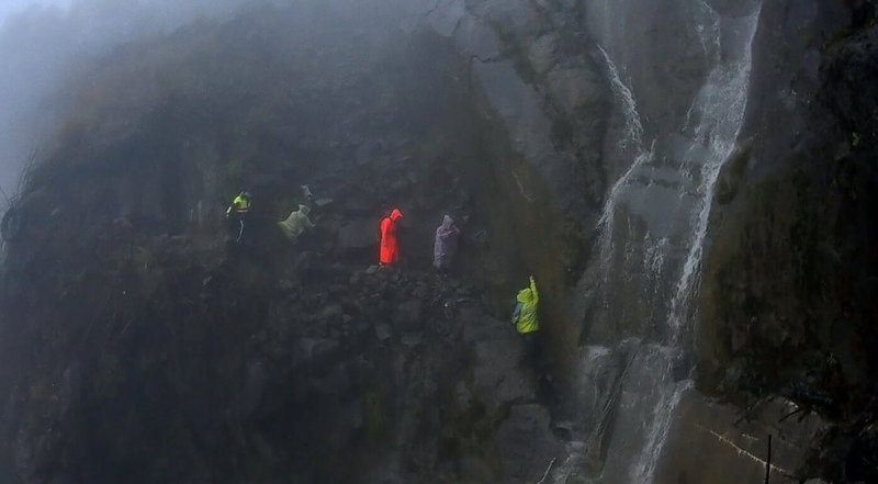 阿里山林鐵眠月線一處隧道崩塌處因15日降雨形成水瀑,3名登山客受困待援,嘉義縣阿里山消防分隊人員趕往救援,待雨勢停,水瀑減緩,立即以人力接駁方式協助3人脫困,均無受傷。(嘉義縣消防局提供)中央社記者黃國芳傳真 111年5月15日