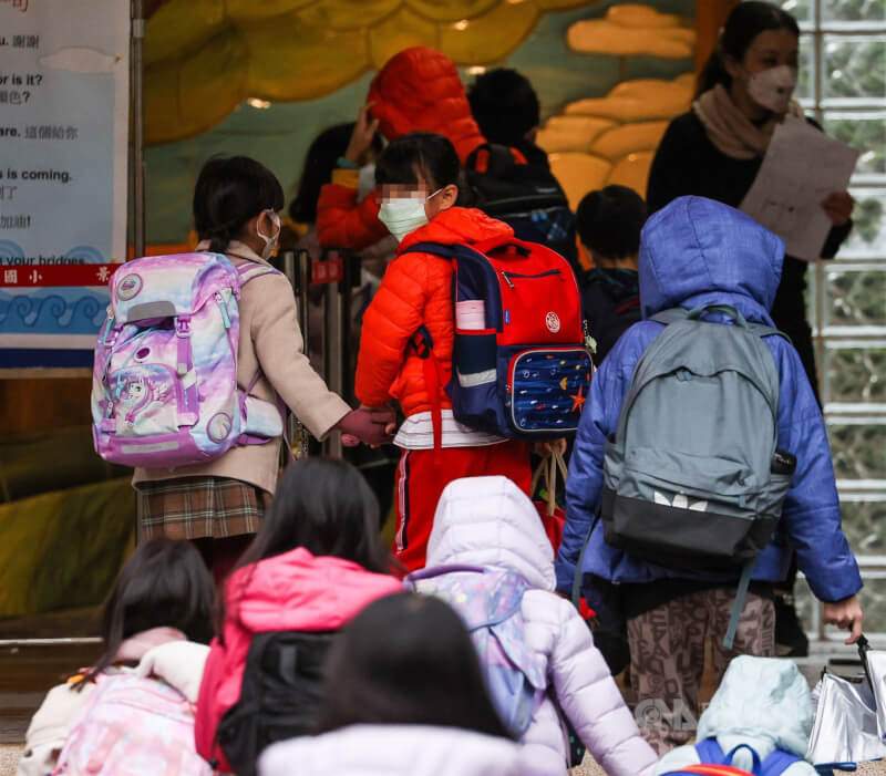 台北市議員游淑慧17日建議高中以下學童下週起暫停到校上課兩週，北市府表示相關規劃18日定案。圖為北市一間國小學生戴口罩到校。（中央社檔案照片）