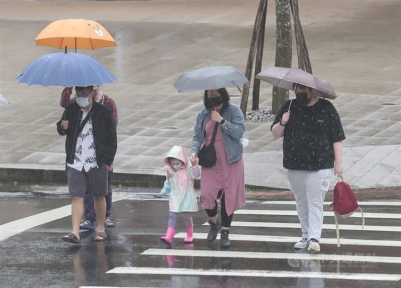 氣象專家吳德榮表示，下一波滯留鋒21至24日影響台灣，需注意瞬間強降雨。圖為民眾撐傘走在北市信義區街頭。（中央社檔案照片）